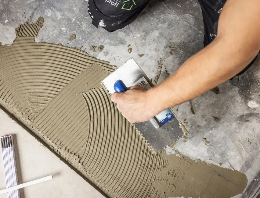 sanierungsprofi Fliesenleger Nahaufnahme Nahaufnahme eines Fliesenlegers von sanierungsprofi der gerade spachtelt