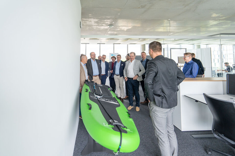 Eine Gruppe von Männern steht vor einem grünen Lampuga Surfboard