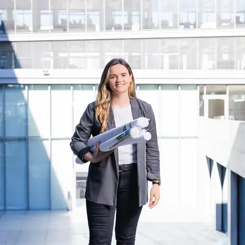 Junior-Projektentwicklung bei weisenburger Junior-Projektentwicklerin mit Plänen im Innenhof der weisenburger-Zentrale