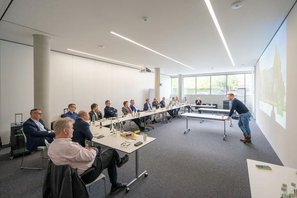 Team presentation Lean Summit 2023 Several weisenburger employees sit in a meeting room and listen to a presentation
