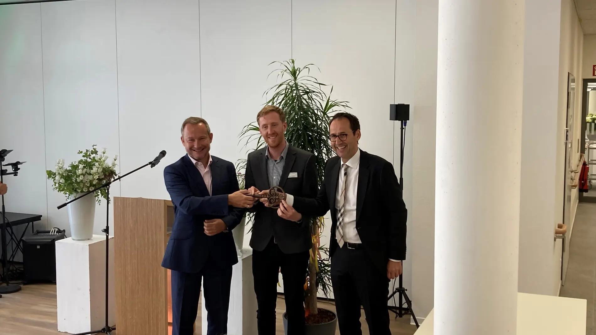 weisenburger-Geschäftsführer übergibt Schlüssel bei Eröffnung von einem Altenpflegeheim Geschäftsführer Matthias Ryzlewicz übergibt zwei Männern einen Schlüssel bei der Eröffnung eines Altenpflegeheim