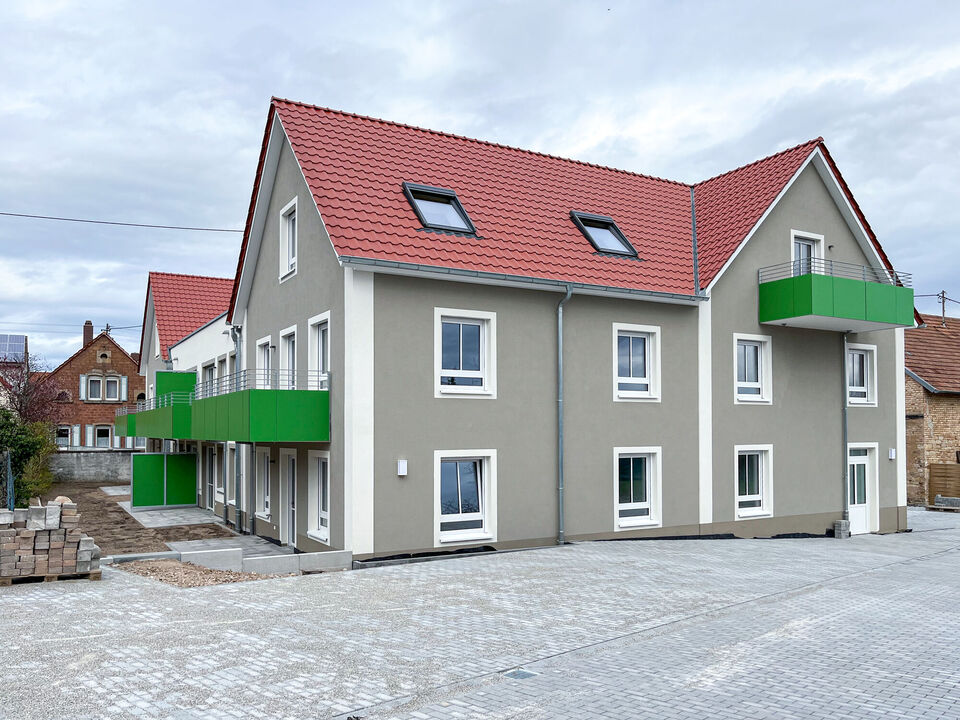 Mehrfamilienhaus mit grauem Anstrich und grünen Balkone