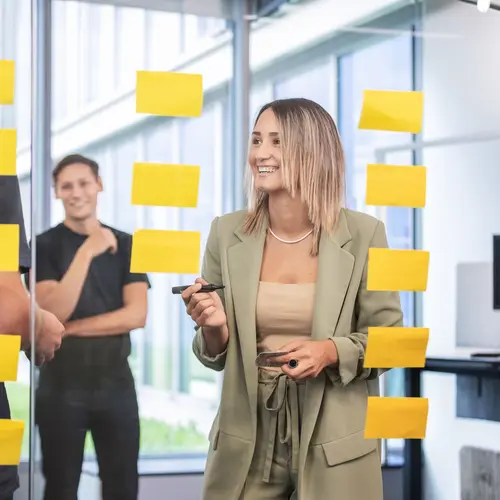 Personalentwicklung Junge Mitarbeiter von weisenburger sammeln an einer Glasscheibe Ideen mit Haftzetteln