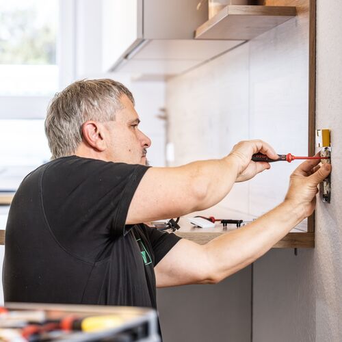 ein Mann installiert einen Lichtschalter an der Wand 