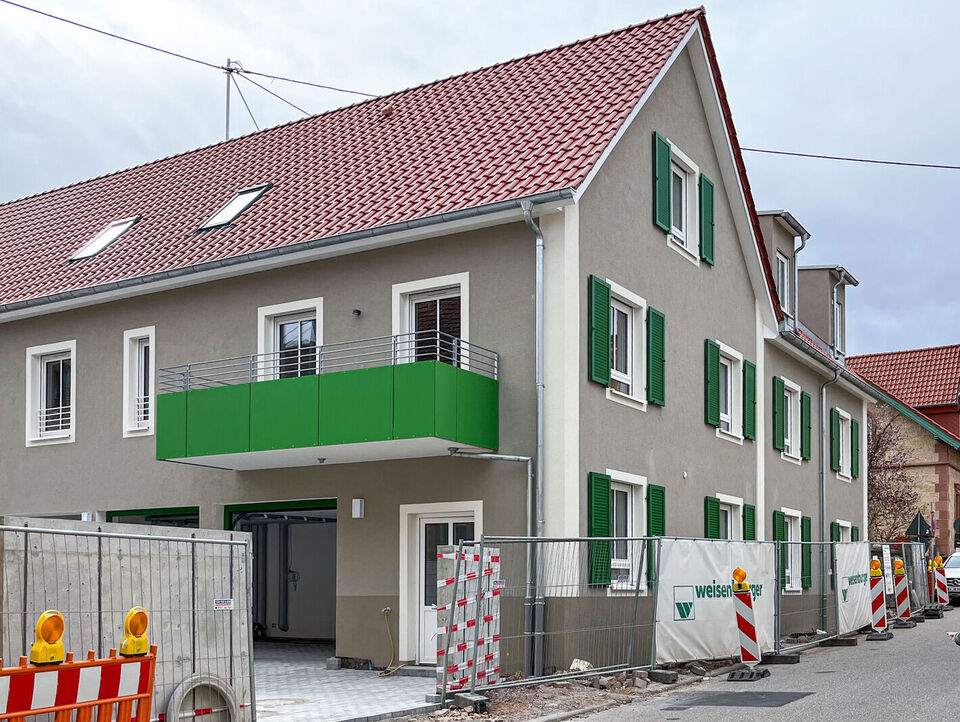 Mehrfamilienhaus mit grauem Anstrich und grünen Balkone