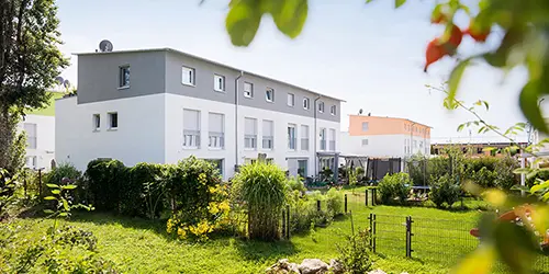 weisenburger-Reihenhaeuser-Emmendingen Vier grau und weiß gestrichene Reihenhaeuser mit grünen Gaerten