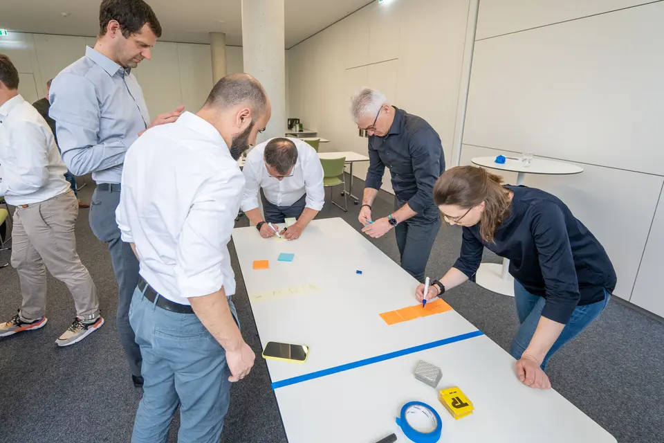 Joint solution optimization at the Lean Summit 2023 Several weisenburger employees stand in front of a table and write notes to compile a complete result