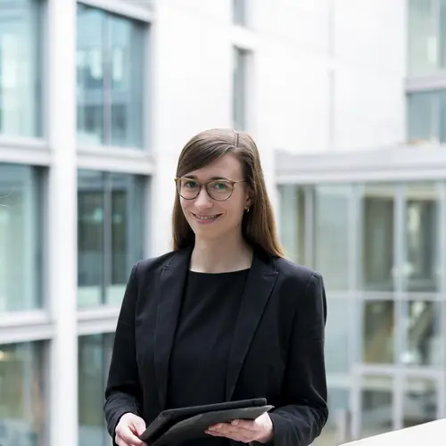 Fonds-Management Eine Frau steht im Innenhof der weisenburger Unternehmenszentrale und hält lächelnd ein Tablet in der Hand