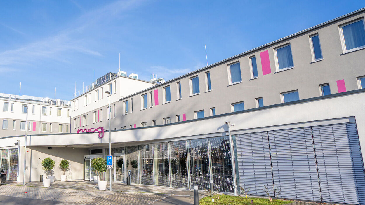 Außenansicht vom Moxy Hotel in Karlsruhe mit Stellplatzen direkt vor der Eingangstuer 