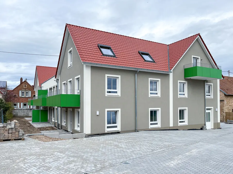 New multi-family house from weisenburger in Speyer Maikammer New apartment building by weisenburger with green balconies and red roofs under a cloudy sky in Speyer Maikammer